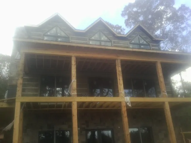 Dormers and porch framing on a large log home under construction — Roof Coating work by our crew in Rialto