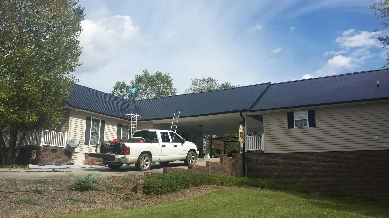 Black metal roof over a home and attached breezeway with ladders set in Rialto
