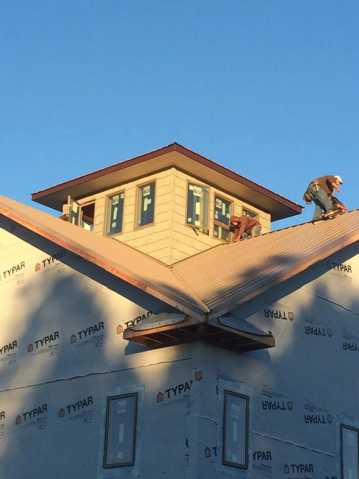 Roofers working around a rooftop cupola on a new metal roof at sunset — Roof Waterproofing in Rialto by Roofing Brothers